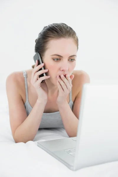 Mujer casual conmocionada usando teléfono celular y portátil — Foto de Stock