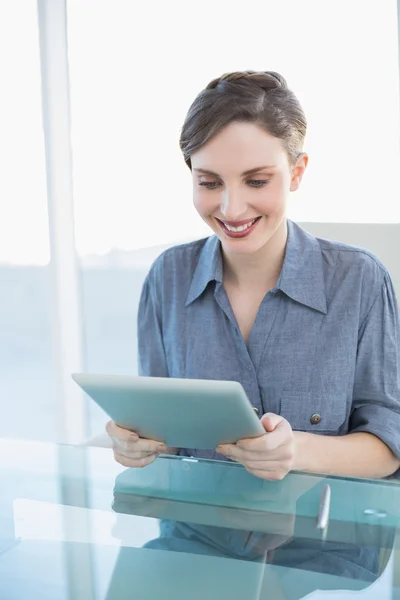 Vrolijke jonge zakenvrouw met behulp van haar Tablet PC zit op haar Bureau — Stockfoto