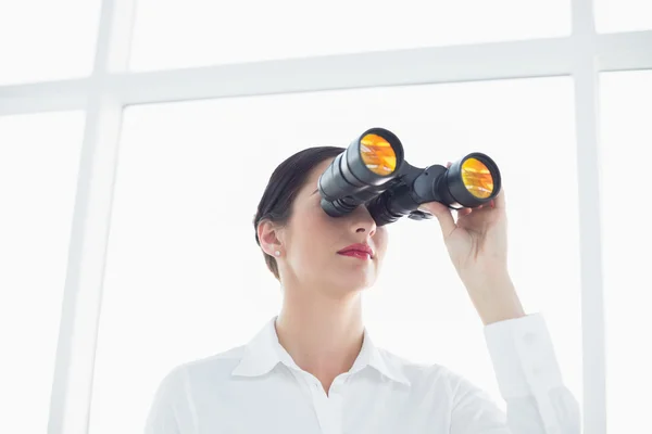 Business woman looking through binoculars in office — Stock Photo, Image