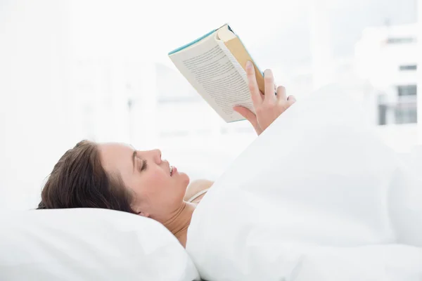 Frau liest Buch im Bett — Stockfoto