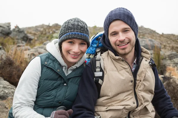 Lächelndes Paar sitzt auf einem Felsen während einer Wanderung — Stockfoto