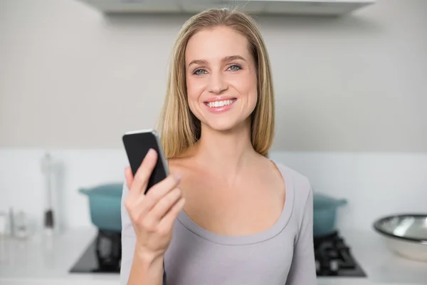 Glada vackra modell håller smartphone tittar på kameran — Stockfoto