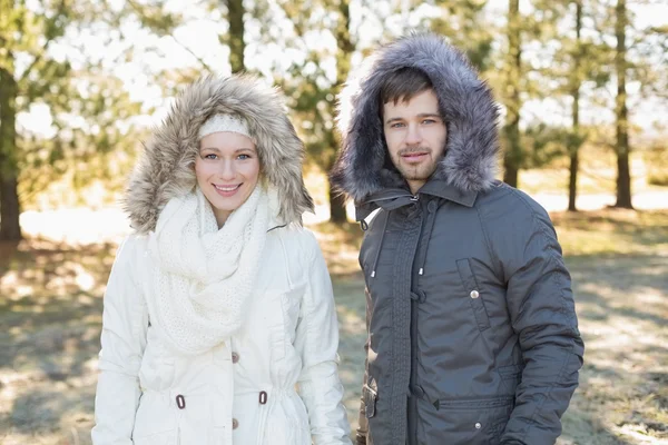 Uśmiechający się para w futro kaptur kurtki w lesie — Zdjęcie stockowe