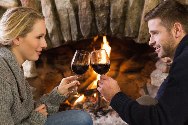 Couple toasting verres à vin devant la cheminée allumée — Photo