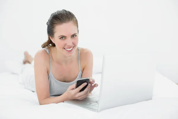 Portret van een ontspannen casual vrouw met behulp van cellphone en laptop — Stockfoto