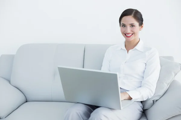 Sorrindo bem vestido jovem mulher usando laptop no sofá — Fotografia de Stock