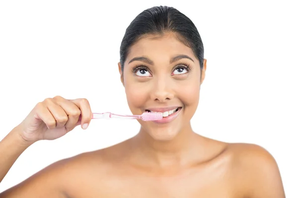 Smiling nude brunette using toothbrush looking up — Stock Photo, Image