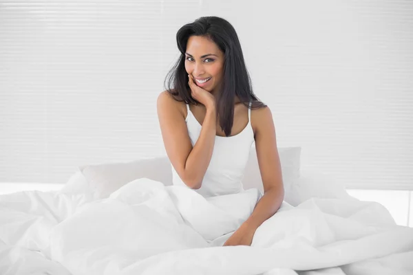 Gorgeous young woman posing sitting on her bed — Stock Photo, Image