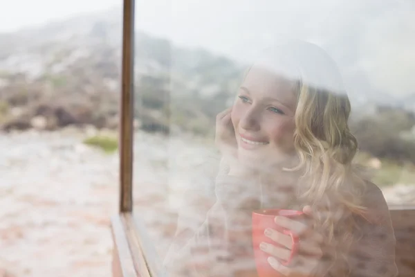 Mujer contenido reflexivo con taza de café mirando a través de la ventana — Foto de Stock