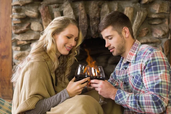 Couple toasting wineglasses in front of lit fireplace — Stock Photo, Image