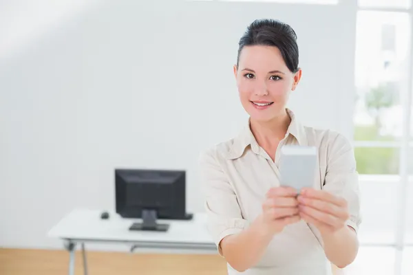 Empresária segurando um celular no escritório — Fotografia de Stock