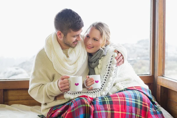 Milující pár v zimě nosit s cups proti okno — Stock fotografie