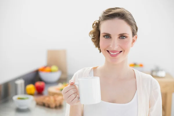 Fröhliche schöne Frau steht in ihrer Küche und hält eine Tasse — Stockfoto