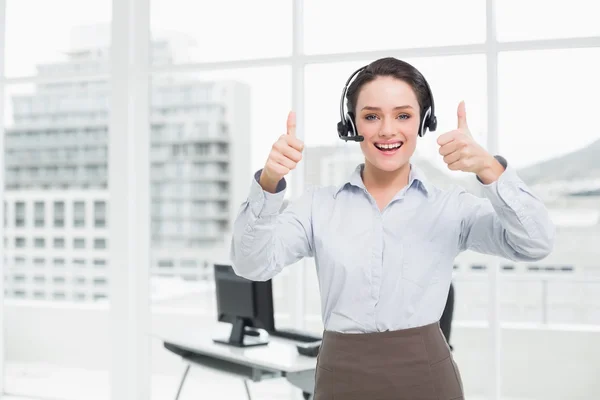 Elegante donna d'affari che indossa auricolare mentre gesticolare pollici in su — Foto Stock