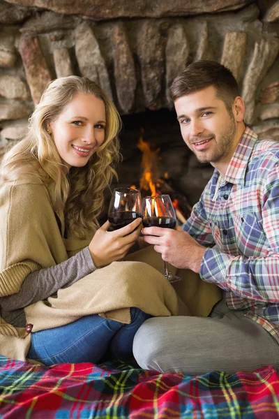 Couple toasting wineglasses in front of lit fireplace — Stock Photo, Image