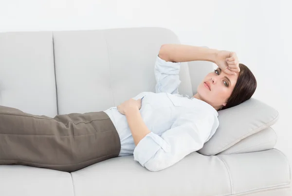 Porträt einer seriösen, gut gekleideten Frau, die auf dem Sofa liegt — Stockfoto