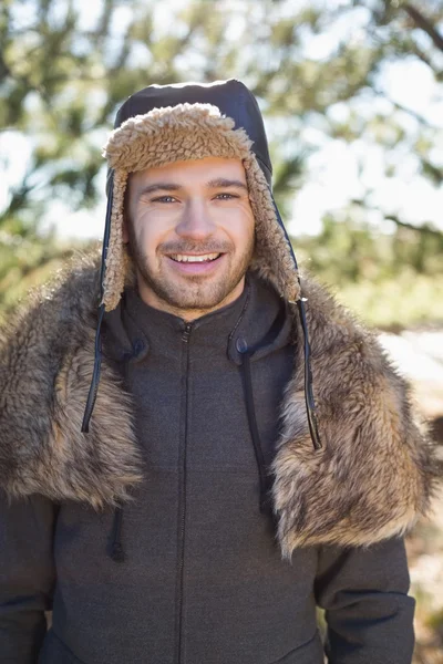 Smiling man in warm clothing standing in forest — Stock Photo, Image