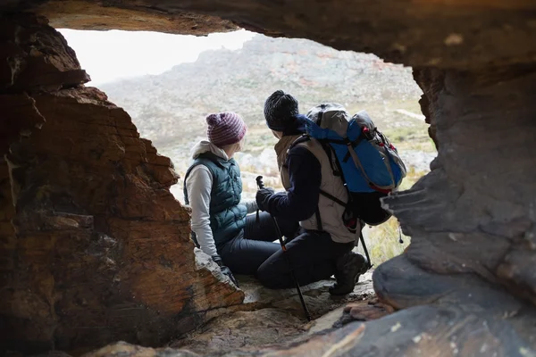 Casal visto através de caverna de rocha enquanto em uma caminhada — Fotografia de Stock