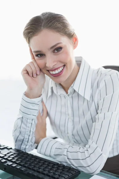 Alegre elegante mujer de negocios sentado en su escritorio sonriendo en camer —  Fotos de Stock