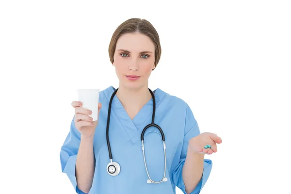 Female doctor holding a plastic cup and pills — Stock Photo, Image