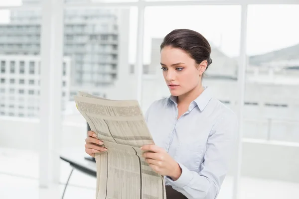 Beautiful businesswoman reading newspaper in office — Stock Photo, Image