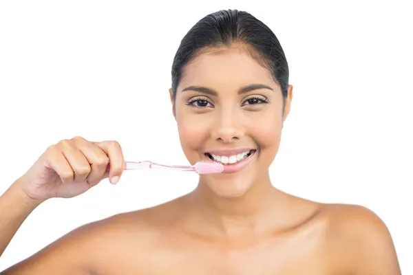 Улыбающаяся обнаженная брюнетка с помощью зубной щетки — стоковое фото