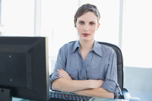 Aantrekkelijke vrouwelijke zakenvrouw zit op haar bureau met gekruiste armen — Stockfoto