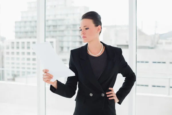 Femme élégante sérieuse lisant un document au bureau — Photo