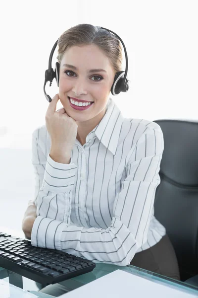 Gleeful female agent wearing headset sitting at her desk Stock Picture