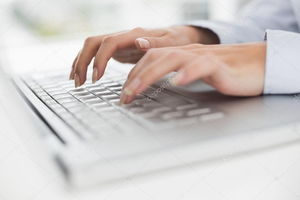 Close-up of hands typing on laptop keyboard