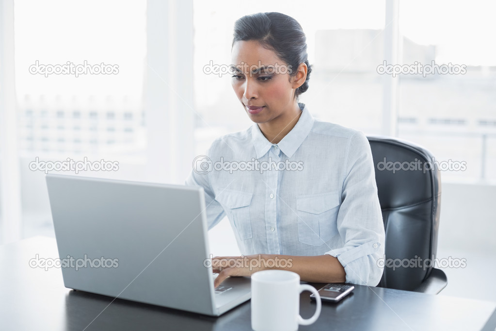 Focused black haired businesswoman working on her laptop