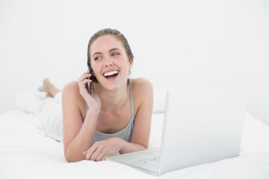 cep telefonu ve dizüstü bilgisayar kullanan neşeli casual kadın