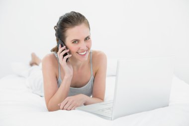 cep telefonu ve dizüstü bilgisayar kullanarak bir gülümseyen casual kadın portresi