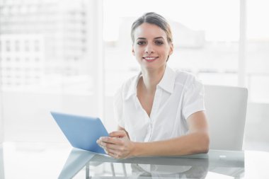 Kameraya bakarak onun tablet ile çalışma neşeli gülümseyen iş kadını
