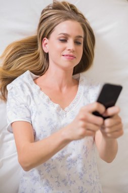 Smartphone kullanarak yatakta yatarken doğal sakin kadın