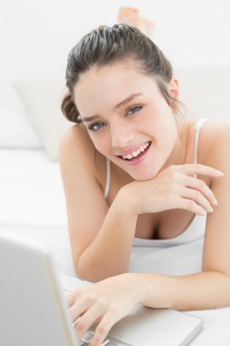 gülümseyen casual kadın yatakta dizüstü kullanarak