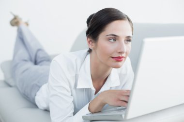 güzel bir kadın kanepede dizüstü kullanarak rahat