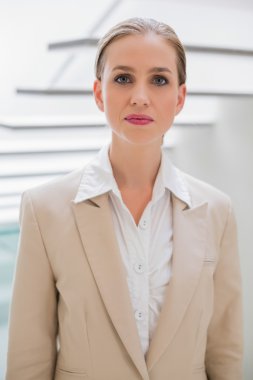 Merdivenlerin yanında duran gülmeyen şık iş kadını
