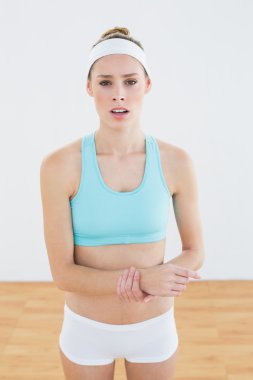 Young slim woman in sportswear touching her injured wrist clipart