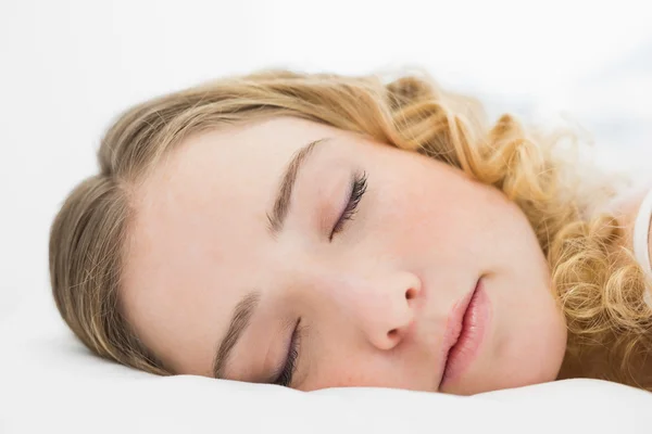 Hübsche, zufriedene Blondine liegt mit geschlossenen Augen im Bett — Stockfoto
