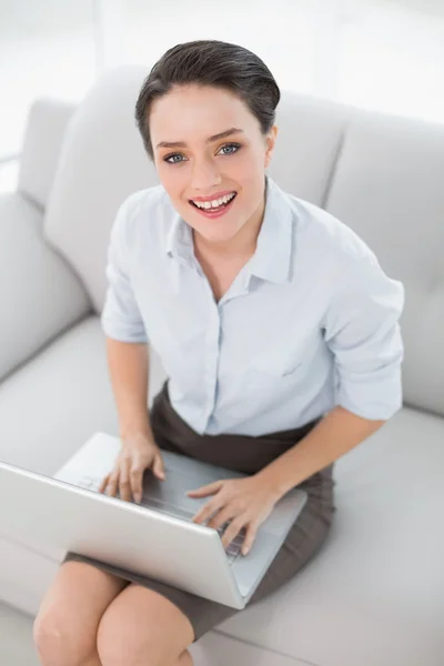 Sonriendo mujer bien vestida usando portátil en sofá — Foto de Stock