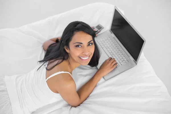 Gelukkig lachende vrouw te typen op haar laptop glimlachen op camera — Stockfoto