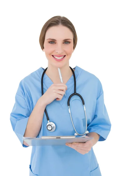 Thinking female doctor keeping a clipboard smiling into the camera — Stock Photo, Image