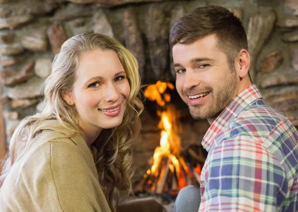 Sonriente joven pareja en frente de la chimenea Lit — Foto de Stock