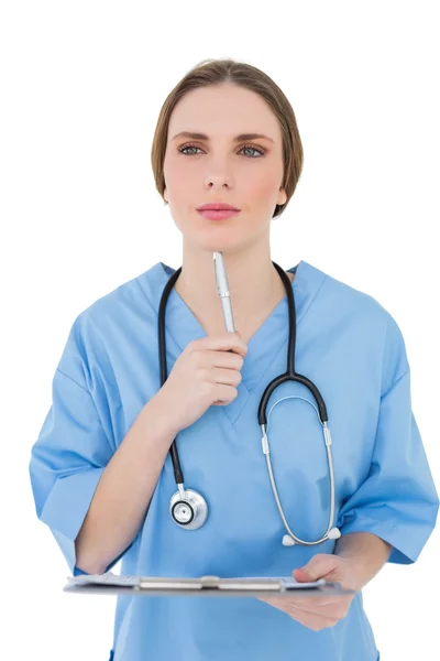 Thinking female doctor holding a clipboard — Stock Photo, Image