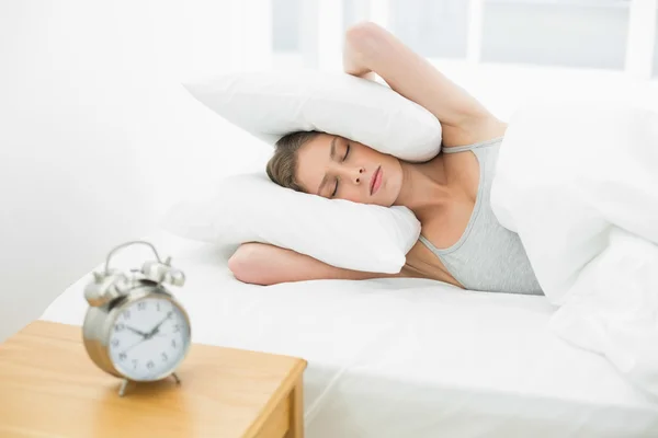 Beautiful woman holding her ears closed by using pillow — Stock Photo, Image