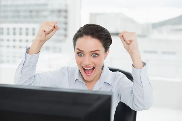 Возбужденная деловая женщина смотрит на экран компьютера в офисе — стоковое фото