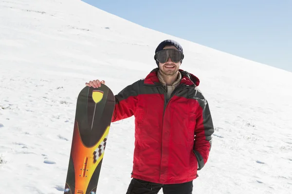 Uomo sorridente con tavola da sci in piedi sulla neve — Foto Stock