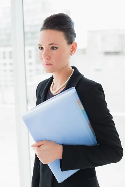 Elegant businesswoman standing against office glass wall — Stock Photo, Image