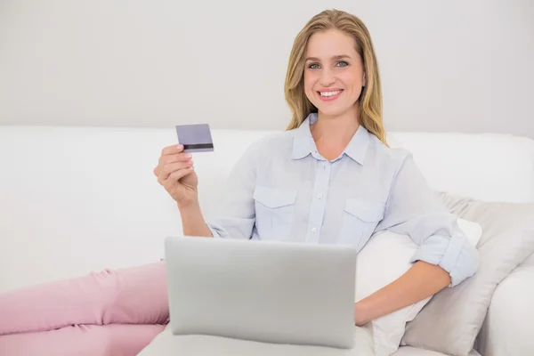 Happy casual blonde relaxing on couch doing online shopping — Stock Photo, Image